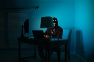 a man with a mask on his computer in the dark